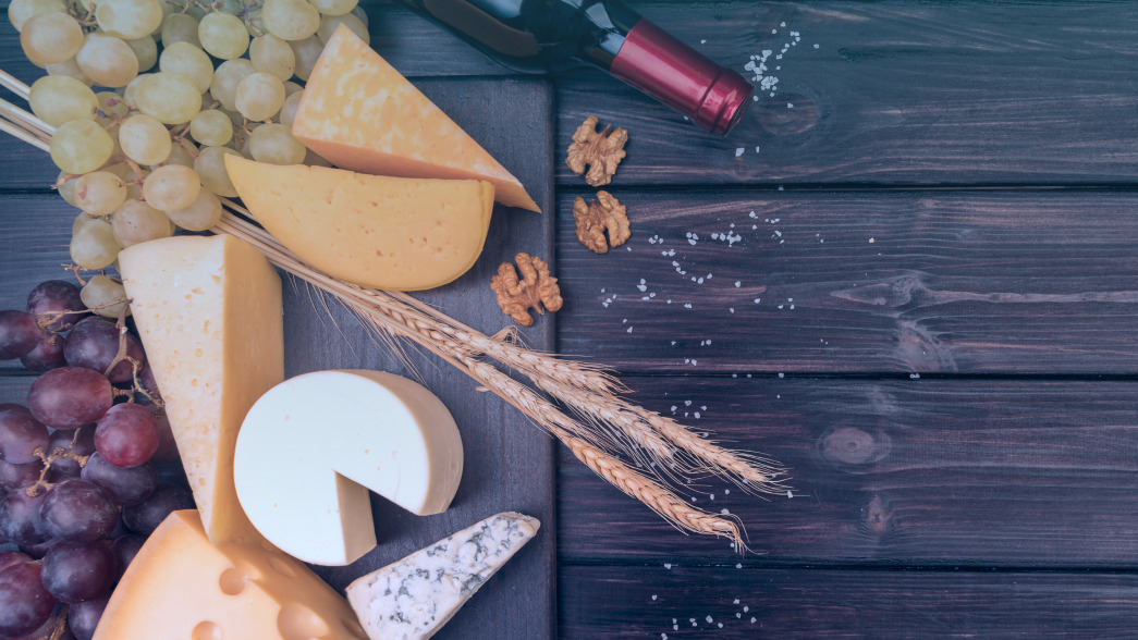 Cheeses with Grapes and Wine on Wooden Surface