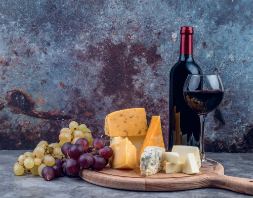 Served Cheeses with Grapes and Wine on Wooden Plate